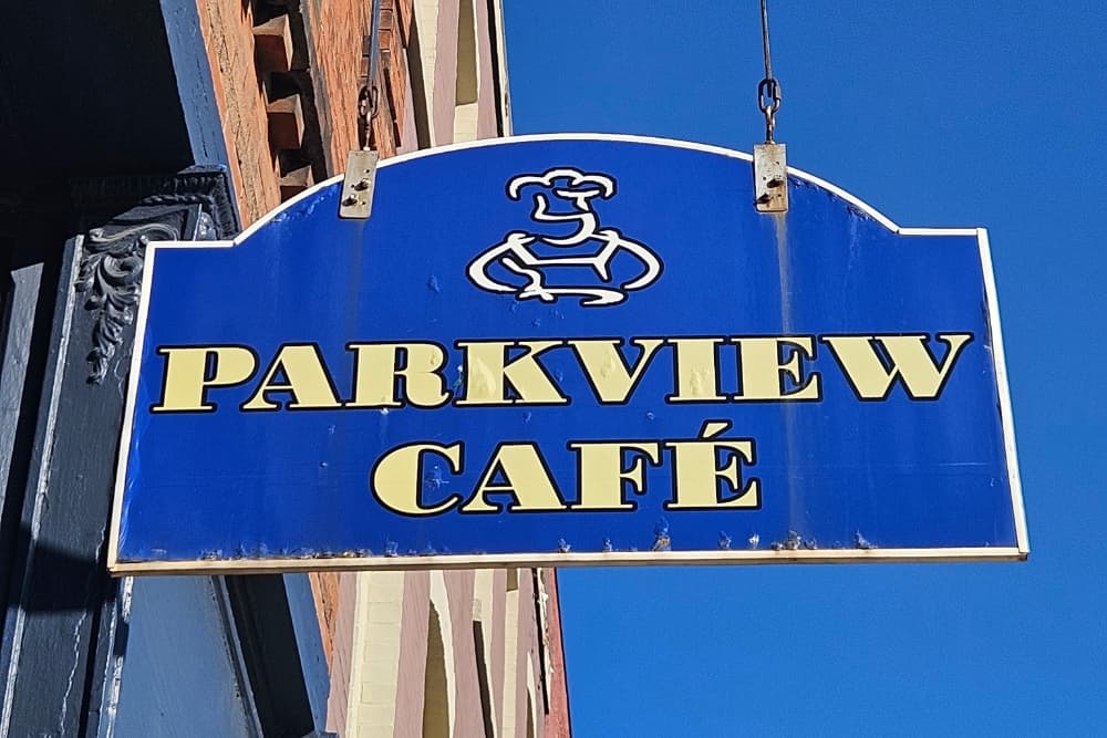 A blue sign with the text "PARKVIEW CAFÉ" and an image of a smiling chef.