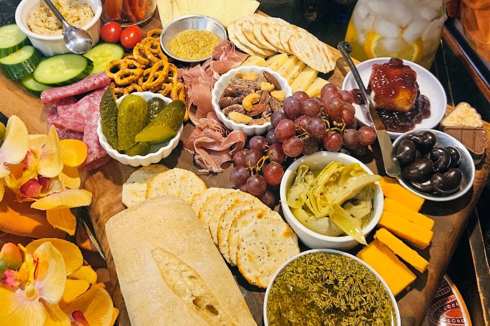 A beautifully arranged charcuterie board featuring assorted meats, cheeses, crackers, fruits, and garnishes.