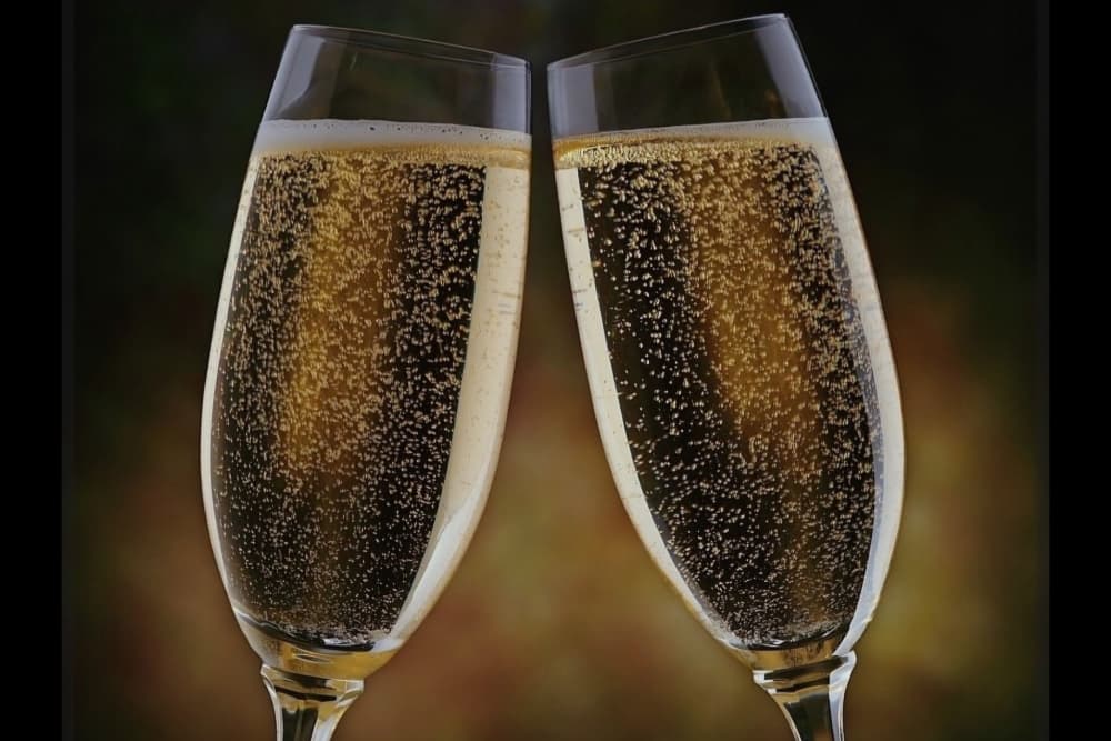 Two glasses of sparkling champagne clink together.